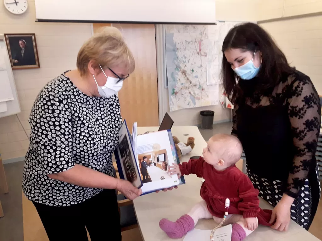 Arja Honkanen esittelee Tetiana Teslialle ja hänen tyttärelleen Valentynalle tietopakettia, joka on koottu Karviaan muuttaneille ulkomaalaisille. Teslian nelihenkinnen perhe on lähtöisin Ukrainasta.