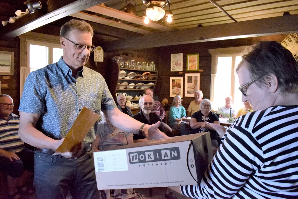 Kihniö-Seuran puheenjohtaja Sirpa Kortesluoma luovuttamassa kokoa 45 olevat Nokian Kontiot Hillopieksu Tapani Törmälle. Törmä veisteli miesten saappaiden kokonumeroidan alkavan juuri 45:stä.
